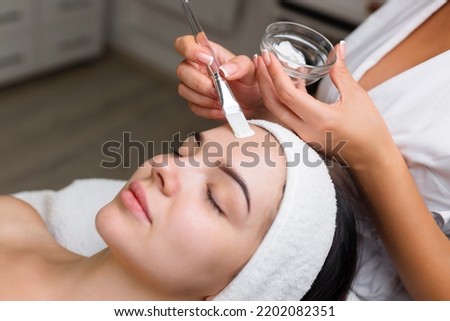 Close-up shot of a woman getting facial treatment with clay mask. Cosmetology and spa Royalty-Free Stock Photo #2202082351