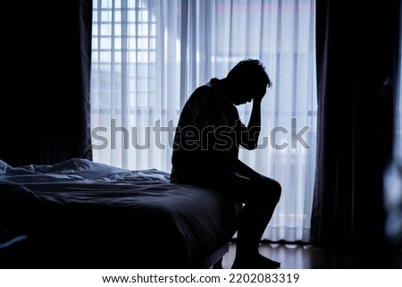 Lonely man silhouette sitting on the bed feeling depressed and stressed in the dark bedroom, Depression and anxiety disorder concept Royalty-Free Stock Photo #2202083319