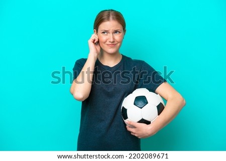 Young football player woman isolated on blue background frustrated and covering ears