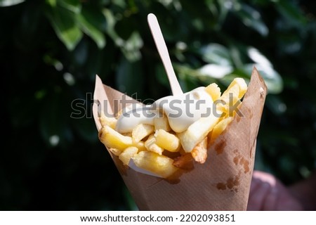 Traditional street food in Belgium and Netherlands, French fried potatoes chips with mayonnaise sauce in paper cone bag Royalty-Free Stock Photo #2202093851