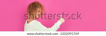 Close-up portrait of attractive surprised girl, showing thumbs up gesture. Success luck concept.