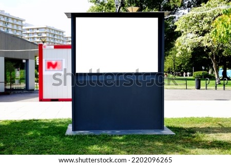 Lightbox ad panel. poster and advert billboard sign. mockup base and background. raster type business communication placeholder. lush green urban park in the summer. blurred residential condominiums.