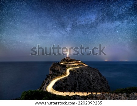 Milky way rising over an illuminated road with light trails at the Far de Formentor lighthouse on the island of Mallorca, Spain Royalty-Free Stock Photo #2202099235