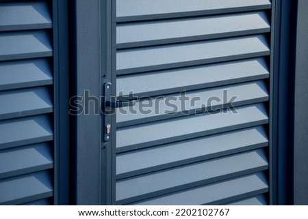 gate and ground made of metal aluminum slats. powder fired paint on door frame and fence with beveled horizontal slats Royalty-Free Stock Photo #2202102767