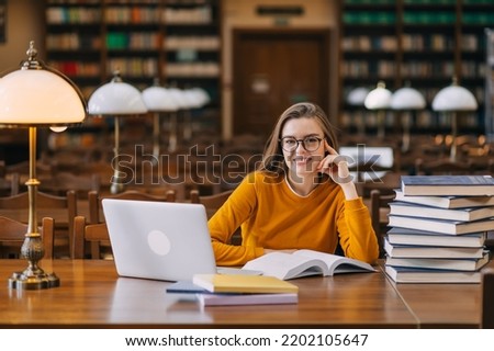 . the student studies in the school library, uses a laptop, and searches for information on the Internet or in books