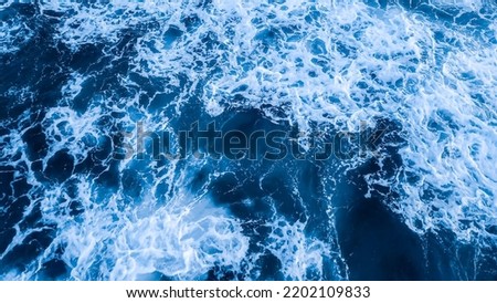 Top view aerial photography white sea foam against the background of the blue sea or ocean. Background, screensaver
