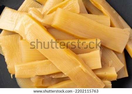 Menma.
bamboo shoots boiled, sliced, fermented, dried or preserved in salt, then soaked in hot water and sea salt.