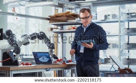 In Robotics Development Laboratory: Future Engineers and Scientists Work on Automated Robotic Arm Prototype. Professional Tech Entrepreneur Inspires People For New Technological Achievements. Royalty-Free Stock Photo #2202118175