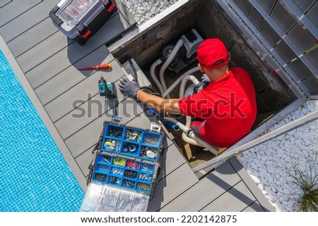 Outdoor Swimming Pool Cleaning and Heating Equipment Seasonal Maintenance Performed by SPA Professional Technician in His 40s. Royalty-Free Stock Photo #2202142875