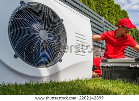 Professional HVAC Worker in His 40s Installing Swimming Pool Heat Pump Outdoor Water Heating Device. Energy Saving Technologies. Royalty-Free Stock Photo #2202142899