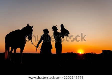 Silhouette of horse and gaucho family at sunset in the countrysi
