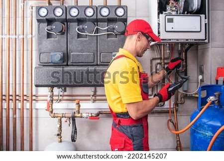 Professional Heating Engineer Making Regular Gas Heating System Performance and Safety Check. Residential Building Heat Installation Maintenance. Royalty-Free Stock Photo #2202145207
