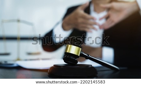 Close up view of auction hammer on the desk in lawyer office and lawyer writing document as courtroom. 
