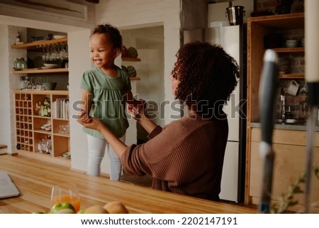Biracial mother holding hands with daughter in kitchen at home
