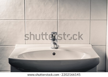 Toilet sink. Bathroom faucet, water tap and WC basin. Dramatic moody light with dark shadows. Public restroom. Grunge rustic or dirty old lavatory home or in hotel. Bad hygiene, wash hands in washroom Royalty-Free Stock Photo #2202166145