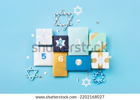 Hanukkah traditional eight nights of light. Gift boxes, stars of David and white candles on blue paper background. Jewish holiday Hanukkah concept. Top view, copy space.