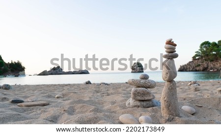 Pyramid stones balance on the sand of the beach with the sea at the background. . 