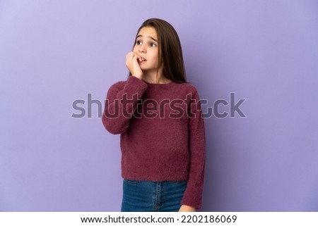 Little girl isolated on purple background is a little bit nervous Royalty-Free Stock Photo #2202186069