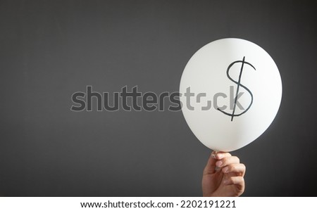 Man hold balloon with a Dollar symbol.