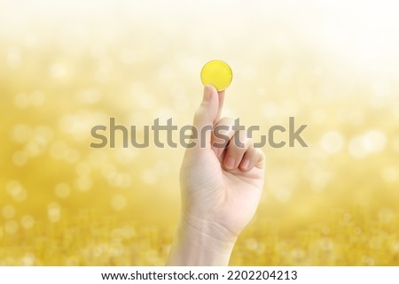 gold coin holding gold coin in hand on a blurred golden yellow bokeh background.