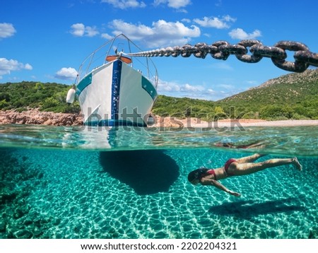 Woman diver is snorkeling on a beautiful sea beach. The bottom half of the picture is occupied by the seabed, on the top - the coast with a yacht and a beautiful sky.