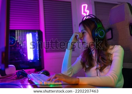 Eyes tired. Gamer and E-Sport online of Asian woman playing online computer video game with lighting effect, broadcast streaming. Her eyes were tired from staring at the screen for a long time. Royalty-Free Stock Photo #2202207463