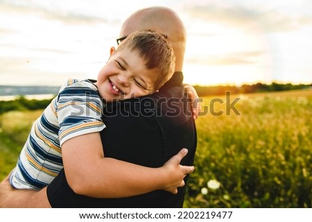 A Portrait of a little boy with down syndrome in sunset on summer season with his father Royalty-Free Stock Photo #2202219477