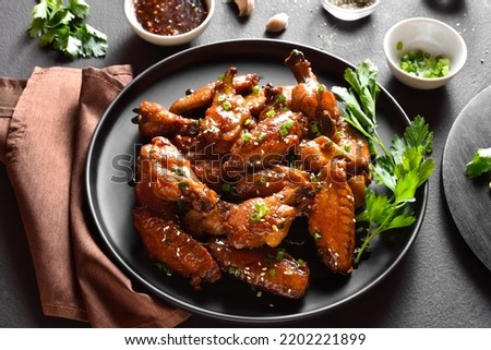 Sticky honey-soy chicken wings on plate over dark stone background. Close up view Royalty-Free Stock Photo #2202221899