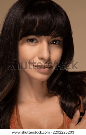portrait of beautiful native American woman with gorgeous hair smiling confidently on neutral background