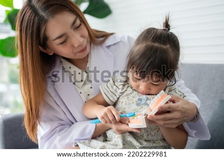 Asian female dentist teaching cute little girl brushing teeth with toothbrush and stomatologist telling girl child about oral hygiene in dental clinic, Education and prevention cavities concept. Royalty-Free Stock Photo #2202229981