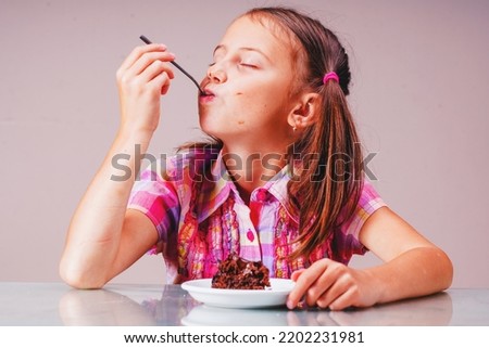 Beautiful happy young girl eating chocolate cake. Horizontal image.