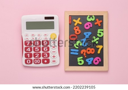 Education concept. Maths. Calculator and chalk board with plastic magnetic numbers on pink background