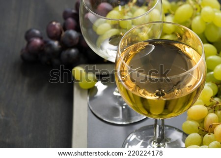 glass of white wine and assorted grapes on a blackboard, close-up