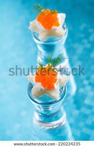 canape with red caviar for Christmas on a blue background, vertical, close-up