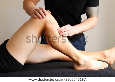 Masseur does legs massage in spa center. Massage of myofascial trigger points on leg of male client to release tension. Rehabilitation, sport therapy medicine. Royalty-Free Stock Photo #2202243197