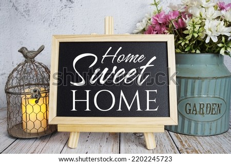 Home Sweet Home text message written on blackboard standing on wooden background