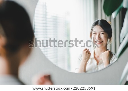 Asian woman looking through the mirror and confident of herself. cheer yourself up Royalty-Free Stock Photo #2202253591