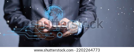 This photo of an Asian man features a modern high-tech financial tech icon who uses the phone to search for business information and contact people around the world. Focus on the hand beside the ball