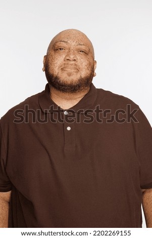 Portrait of a gorgeous multiracial man in his 50's standing confidently on a white seamless.