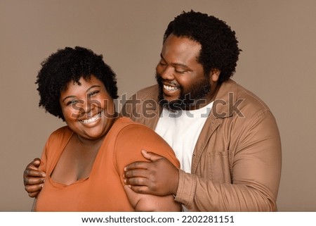 Portrait of an African American man in his 30's and an African American woman in her 20's laughing together on a neutral background. Royalty-Free Stock Photo #2202281151