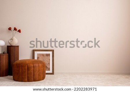 Minimalist composition of elegant and outstanding space with copy space, brown pouf, poster, wooden stand, decoration, vase with dried flowers and accessories. Creative home decor. Template. Royalty-Free Stock Photo #2202283971