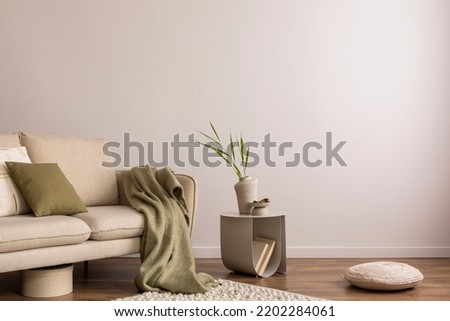 Interior design of living room with copy space, beige sofa, side table, leaf in vase, pouf, elegant accessories and boucle rug. Beige wall. Minimalist home decor. Template.  Royalty-Free Stock Photo #2202284061