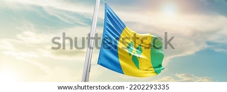 Saint Vincent and the Grenadines national flag waving in beautiful sky.