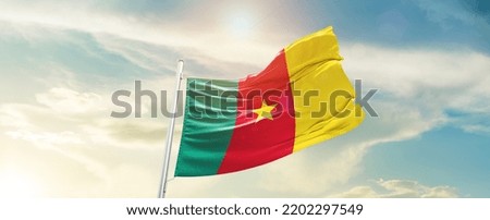 Cameroon national flag waving in beautiful sky.