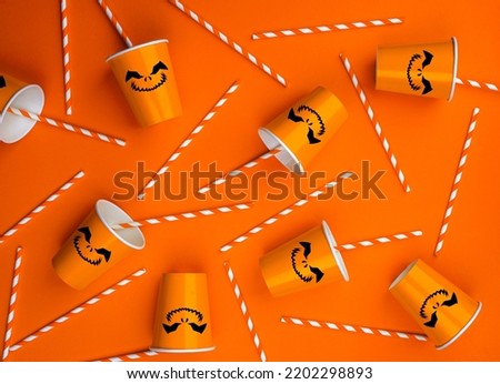 Halloween party background with Paper cup with Jack lantern face decoration. Disposable cup made of recycled paper orange colors. Pattern for outumn october holiday all saints day celebration.