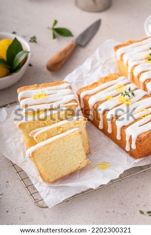 Classic lemon pound cake with powdered sugar glaze sliced on parchment paper topped with lemon zest
