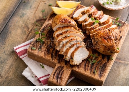 Roasted or seared chicken breast sliced on a cutting board with herbs and spices Royalty-Free Stock Photo #2202300409