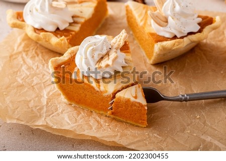 Slice of pumpkin cheesecake swirl pie topped with whipped cream with a bite taken out, original Thanksgiving dessert idea