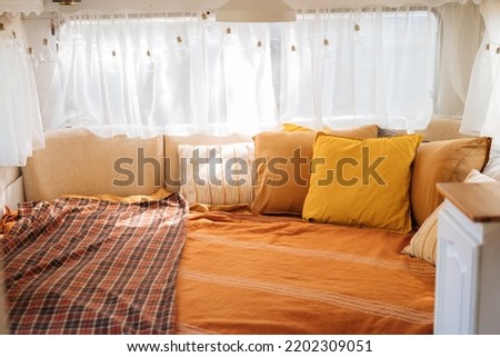 Cozy bedroom interior inspired by autumn colors. Pillows, light bed of a mobile home on wheels. Light bulbs.