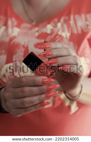 Female hands with long nails and neon orange nail polish